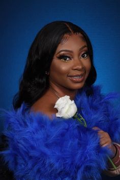 a woman in a blue fur coat holding a white rose