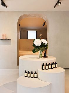 a vase with white flowers sitting on top of a counter next to bottles of perfume