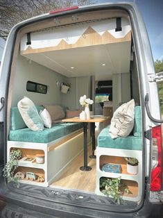 the back end of a van with two couches and a table in it's cargo area