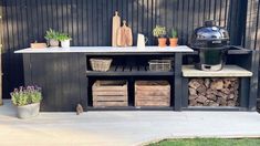 a bbq grill sitting on top of a wooden table next to potted plants