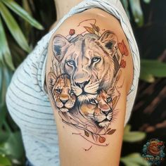 a woman with a lion and cub tattoo on her arm, next to some leaves