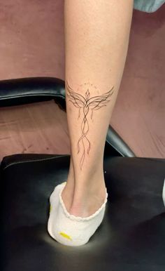 a woman's foot with a tattoo on her left leg, sitting in a chair