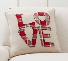 a love pillow on a couch with the word love spelled out in red and white