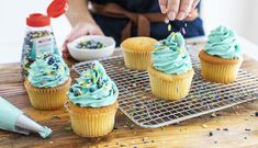 a person decorating cupcakes with blue frosting and sprinkles