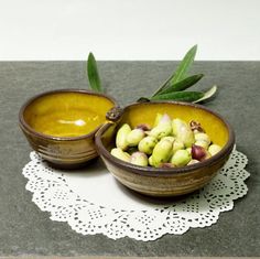 two brown bowls filled with food sitting on top of a table next to a doily