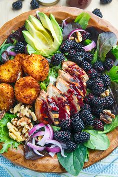 a wooden bowl filled with meat, fruit and veggies