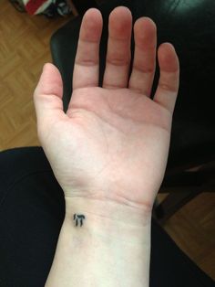 a person's hand with a small tattoo on their left wrist and the letter t