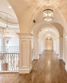 an empty hallway with wooden floors and chandeliers