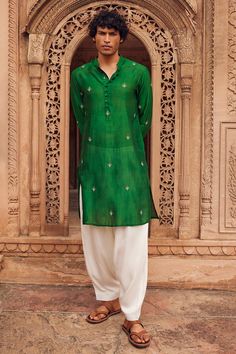 Green kurta in chanderi silk base with all over bloom embroidery. Paired with contrasting salwar. Components: 2 Pattern: Embroidery, Pintucked Type Of Work: Floral Neckline: Mandarin Collar Sleeve Type: Long Fabric: Chanderi Silk, Cotton Silk Color: Green Other Details:  Length: Kurta: 45.5 inches Salwar: 40 inches Closure:  Kurta: Front potli buttons Occasion: Sangeet, Mehendi and Puja - Aza Fashions Men Navratri Kurta Design, Luxury Green Raw Silk Sherwani, Printed Mens Kurta, Luxury Dola Silk Unstitched Wedding Suit, Mehendi Kurta For Men, Transitional Embroidered Raw Silk Lawn Suit, Traditional Silk Lawn Suit For Eid, Festive Cotton Silk Lawn Suit For Transitional Season, Transitional Festive Cotton Silk Lawn Suit