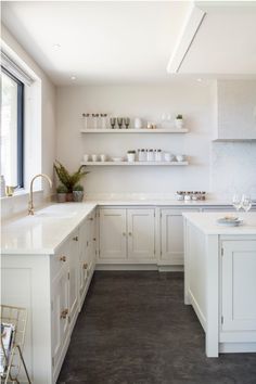 a large kitchen with white cabinets and counter tops, along with open shelves on the wall