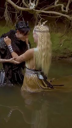 two people dressed in costumes are standing in the water with their arms around each other