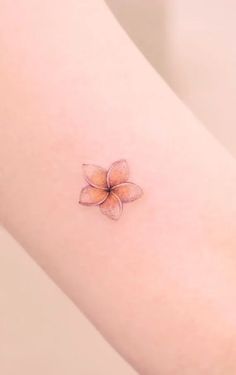 a small flower tattoo on the right side of the arm, with an orange center