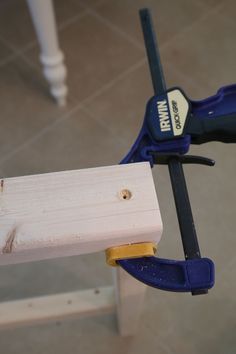 a piece of wood being held up by a pair of pliers on a table