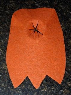 an orange piece of cloth with a spider on it sitting on a black counter top