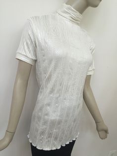 "Pearl white short sleeve turtle neck.  Off-white tunic blouse in luscious off-white ribbed knit. Body conforming 2-way stretch fabric reflects a gorgeous silver sheen on neutral cream background. Wear untucked or tucked.  26\" long from center back neck to hem.  Shoulder to shoulder width, 18\".  Sleeve length, 8\".  Designed to fit a variety of women's shapes. US sizes 6, 8, 10 (M-L). Hand wash warm inside out; air dry. Do not iron." Fitted White Top With Ribbed Neckline, Elegant Short Sleeve Tops With Ribbed Neckline, Elegant Short Sleeve Top With Ribbed Neckline, White Tops With Ribbed Neckline For Spring, White High Neck Top For Spring, Turtle Neck Blouse, White Tunic Blouse, White Tunic, Knit Short