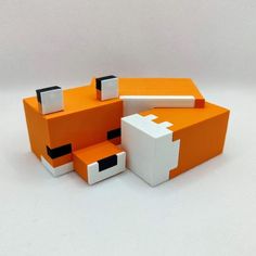 an orange and white box with two black squares on it's sides, sitting on a white surface