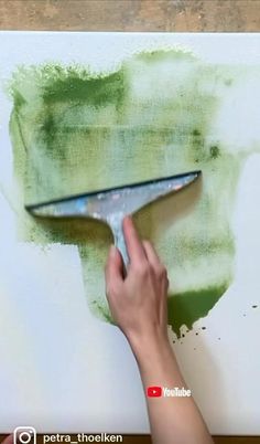 a person is using a paint brush to paint a wall with green and white colors