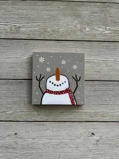 a snowman with a red hat and scarf on it's head is standing in front of a wooden wall