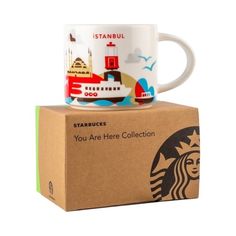 two starbucks mugs sitting on top of each other next to a cardboard box with an advertisement for starbucks