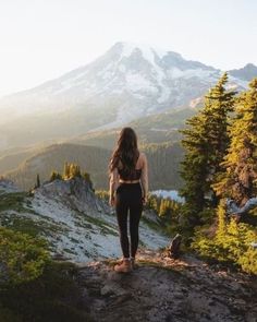 a woman standing on top of a mountain with her back to the camera