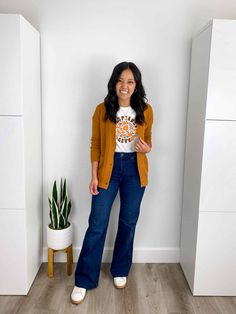 yellow cardigan sweater + yellow and brown and white graphic tee + dark wash flare jeans + white sneakers + gold earrings + gold necklace Bright Yellow Cardigan Outfit, Yellow Cardigan Outfit, Dark Washed Jeans Outfit, Yellow Cardigan Outfits, Jeans White Sneakers, Super Casual Outfits, Yellow Graphic Tee, Dark Sweater, Flare Jeans Outfit