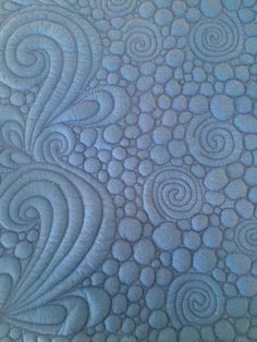 a close up view of a quilted surface with circles and spirals on it