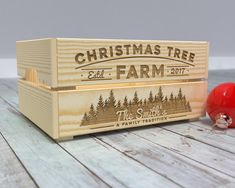 a wooden box with a christmas tree farm logo on it and two ornaments next to it