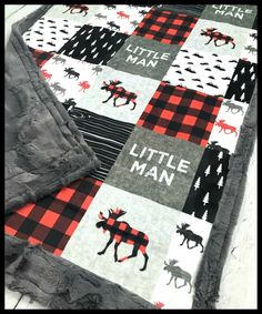 a baby blanket with moose and buffalo print on it, sitting on top of a bed