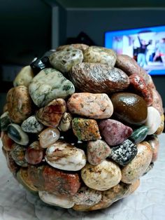 there is a ball made out of rocks on the table with a television in the background