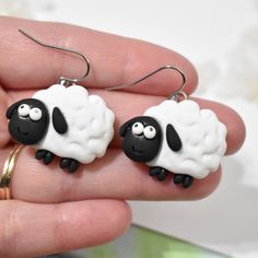 two black and white sheep earrings are being held in someone's hand