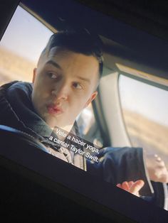 a man driving in the back seat of a car and making a funny face with his tongue out