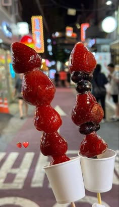 two cups filled with jelly and strawberries sitting on top of each other in front of a street