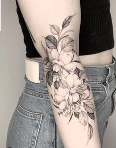 a woman's arm with flowers on it and a black and white tattoo design