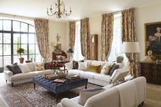 a living room filled with lots of furniture next to a window covered in drapes