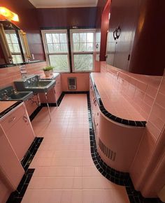 a bathroom with pink tiles and black counter tops, along with two sinks in the middle