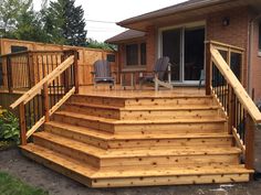 a wooden deck with chairs on it next to a house