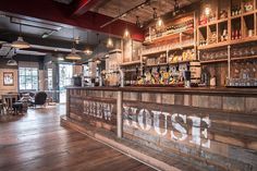 the inside of a restaurant with wooden floors and shelves filled with liquor bottles on top of it