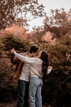 an engaged couple kissing in the woods