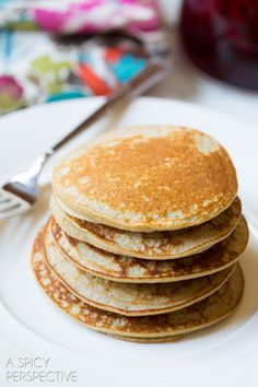 a stack of pancakes sitting on top of a white plate next to a knife and fork