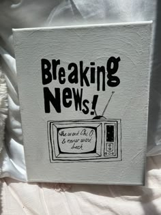 a book with the words breaking news written in black ink on it, sitting on a bed