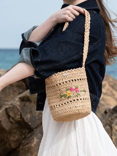 a woman carrying a crocheted purse on the beach