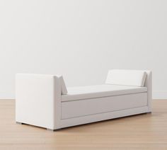 a white couch sitting on top of a hard wood floor next to a white wall