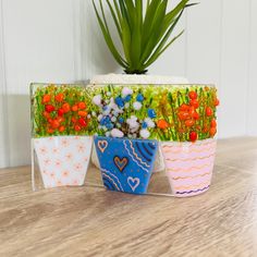 three flower pots sitting on top of a wooden table