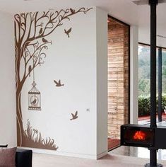 a living room with a fire place and tree wall decal on the wall next to it