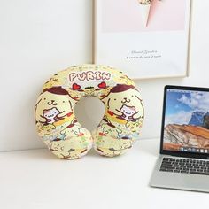 an open laptop computer sitting on top of a desk next to a donut pillow