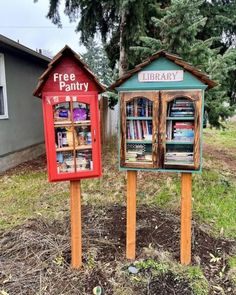 two wooden bookshelves sitting next to each other in front of a tree filled field