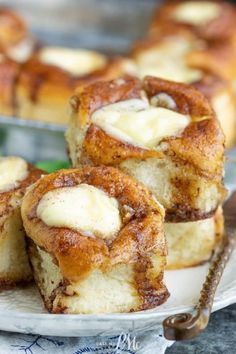 some cinnamon rolls are on a white plate and one has been cut into small pieces