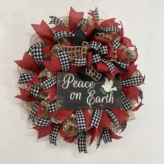 a wreath that says peace on earth with red and black bows hanging from the front