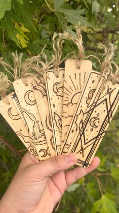 a hand holding five wooden tags with designs on them