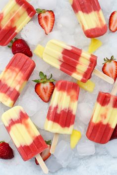 several popsicles with strawberries on top of ice